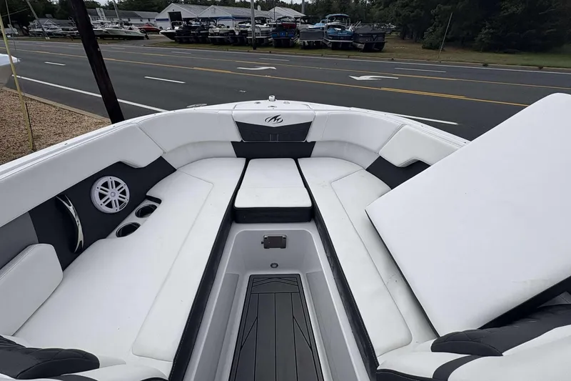 Slide: The Image of 2023 Monterey M-22 boat interior with white seating and cup holders, parked near a road. - 10