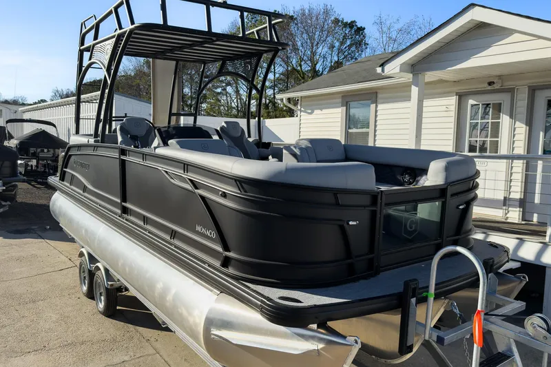 Slide: The Image of 2026 Godfrey Monaco 235 Sun Deck boat, sleek black design, docked near a white building. - 26