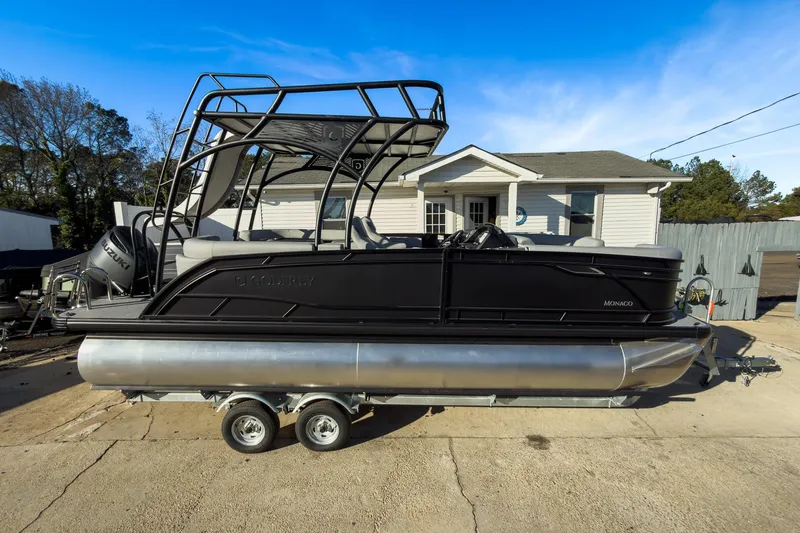 Slide: The Image of 2026 Godfrey Monaco 235 Sun Deck boat on trailer, parked outside a house. - 27
