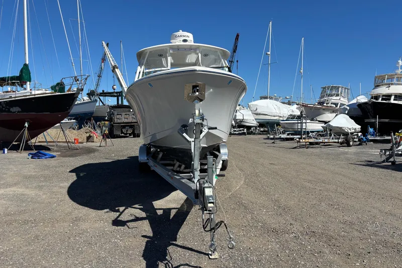 Slide: The Image of 2024 Cobia 280 Dual Console boat on trailer in a marina storage area. - 21