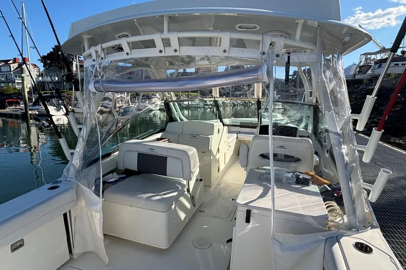 Slide: The Image of 2024 Cobia 280 Dual Console boat interior at marina, showcasing seating and fishing equipment. - 3