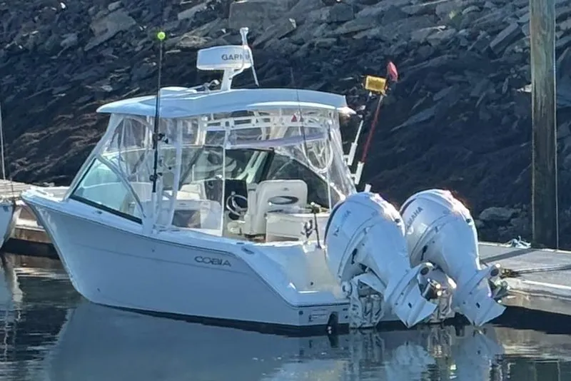 Slide: The Image of 2024 Cobia 280 Dual Console boat docked with twin outboard engines. - 6