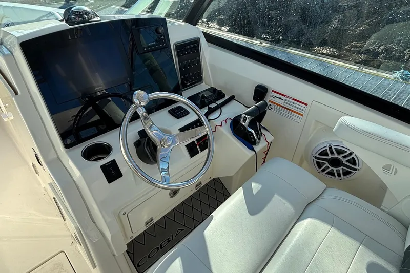 Slide: The Image of 2024 Cobia 280 Dual Console boat cockpit with steering wheel and control panel. - 9