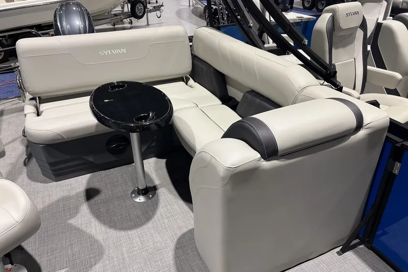 Slide: The Image of 2026 Sylvan Mirage 822 CLZ boat interior with plush seating and a sleek black table. - 8