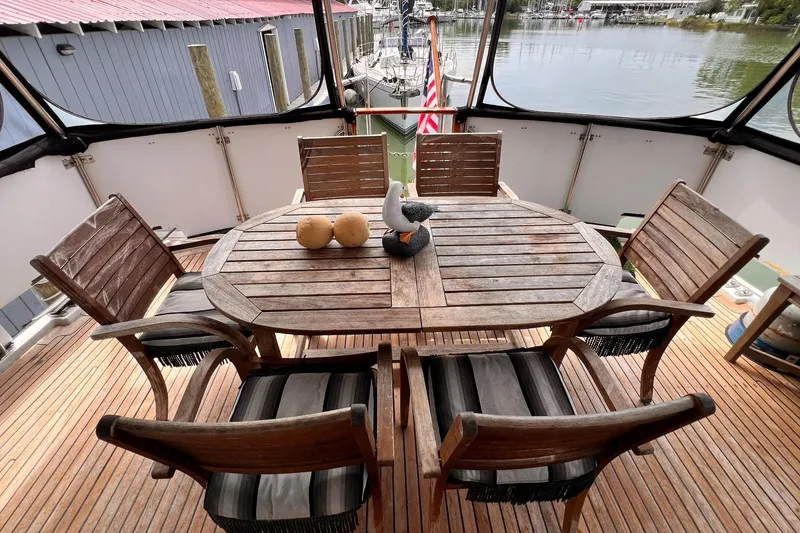 Slide: The Image of Outdoor dining area on 1985 Hartman-Palmer 60 Flush Deck Motor Yacht, featuring wooden table and chairs. - 16
