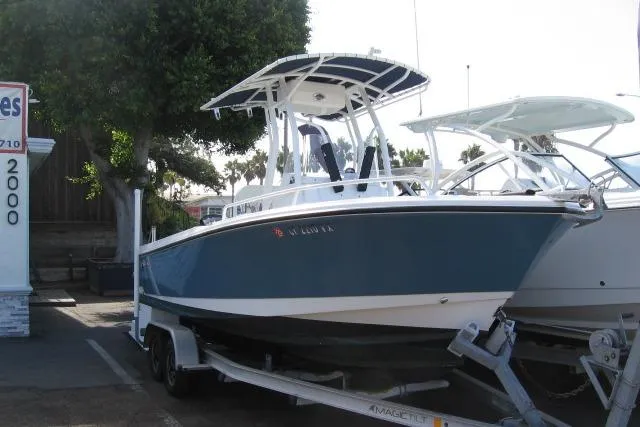 Slide: The Image of 2024 Edgewater 208CC boat on trailer, parked outdoors, featuring sleek blue and white design. - 13