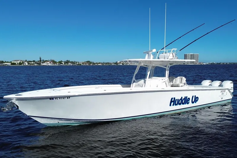 Slide: The Image of 2018 Jupiter 38 FS boat named "Huddle Up" on calm water under clear blue sky. - 2