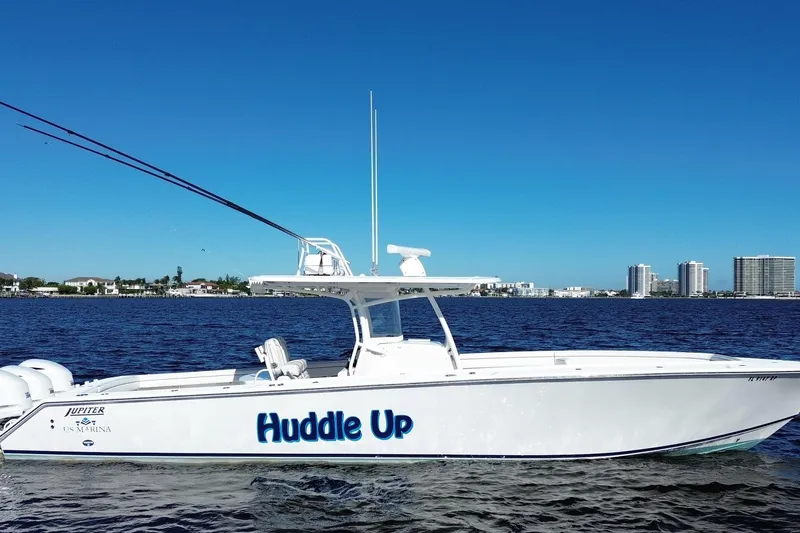 Slide: The Image of 2018 Jupiter 38 FS boat named "Huddle Up" on water with city skyline background. - 24