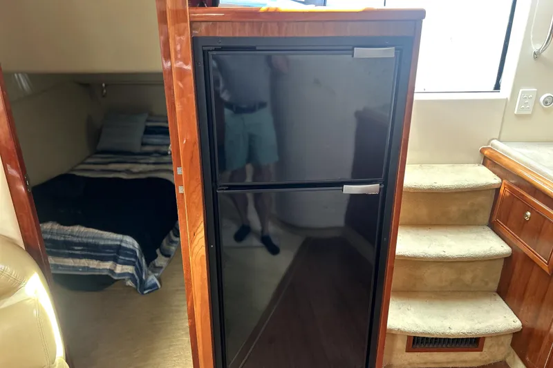 Slide: The Image of Interior of 2004 Wellcraft 47 Excalibur showing a compact kitchen area with fridge and stairs. - 23