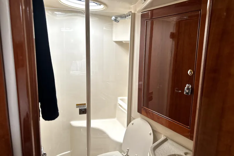 Slide: The Image of 2004 Wellcraft 47 Excalibur bathroom with shower, wooden cabinet, and toilet. - 30