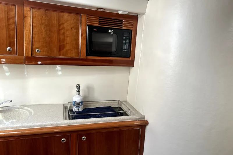 Slide: The Image of 2004 Wellcraft 47 Excalibur yacht interior with wooden cabinets and kitchenette. - 33