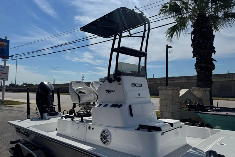 Slide: The Image of 2026 SCB R24 boat with elevated console and seating, parked near palm tree. - 9
