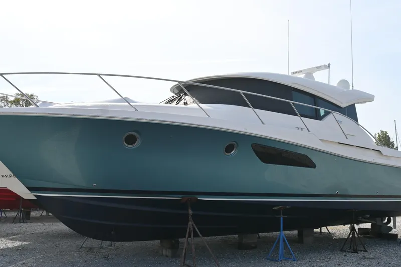 Slide: The Image of 2017 Tiara 44 Coupe yacht docked at marina, surrounded by other boats. - 12