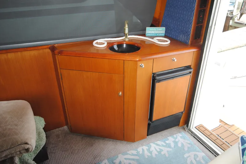 Slide: The Image of 1999 Ocean Yachts 45 Super Sport interior with sink, mini fridge, and wooden cabinetry. - 21