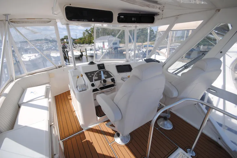 Slide: The Image of 1999 Ocean Yachts 45 Super Sport helm with white seating and wooden flooring. - 5