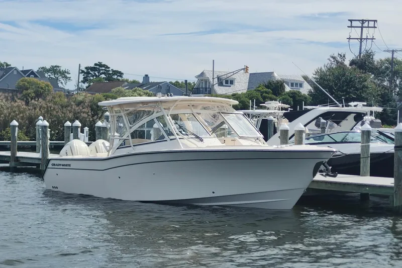 Slide: The Image of 2026 Grady-White Freedom 307 boat docked at marina, clear sky, waterfront homes in background. - 4