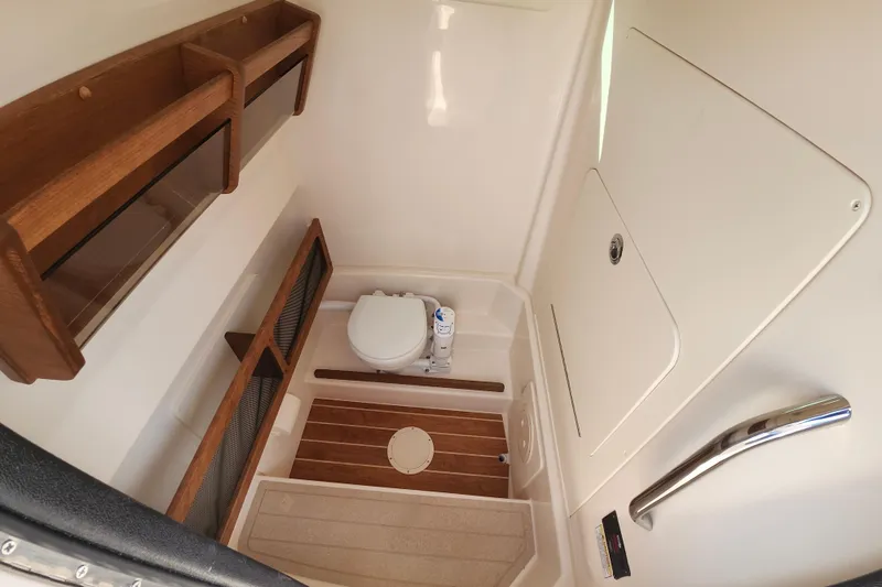 Slide: The Image of 2026 Grady-White Canyon 271 boat interior with compact bathroom and wooden accents. - 14