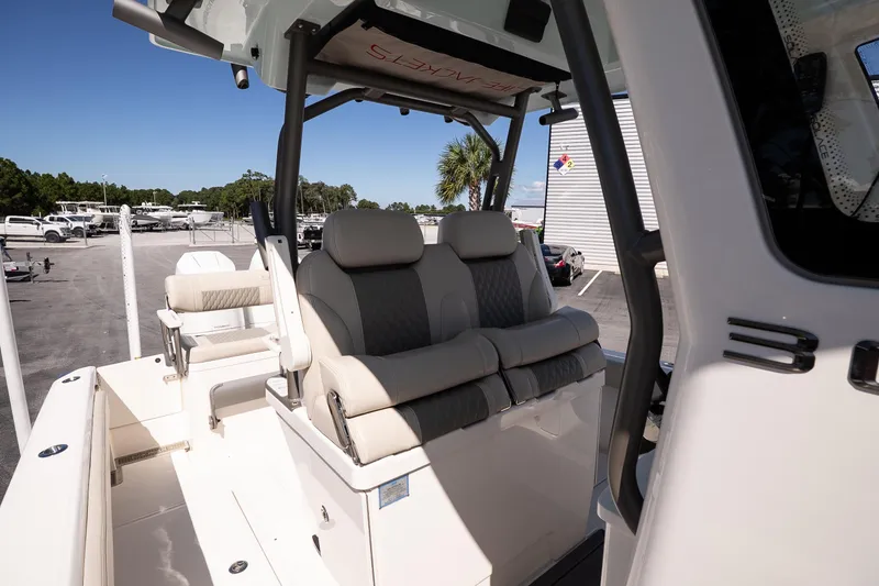 Slide: The Image of 2026 Solace 30 HCS boat interior with seating and storage, surrounded by palm trees. - 17