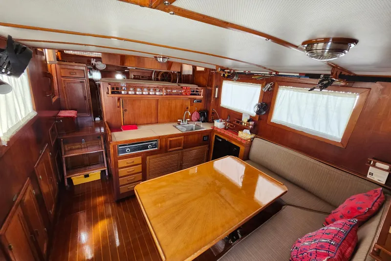 Slide: The Image of Interior of 1988 Sundowner Tug 30, featuring wooden cabinetry, dining area, and compact kitchen. - 11