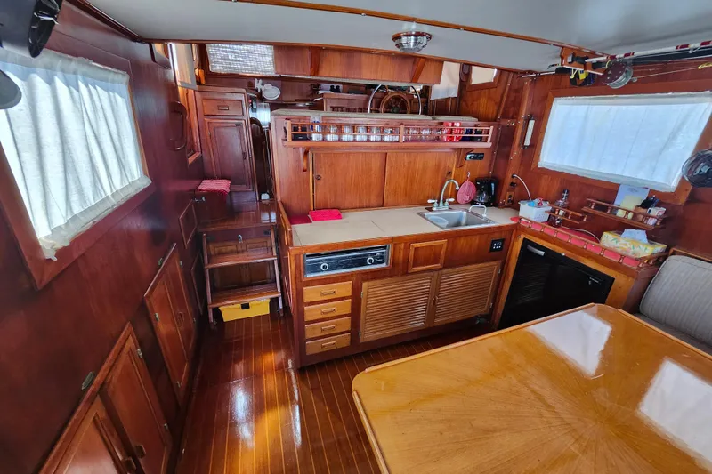 Slide: The Image of Interior of 1988 Sundowner Tug 30, featuring wooden cabinetry and compact kitchen area. - 12