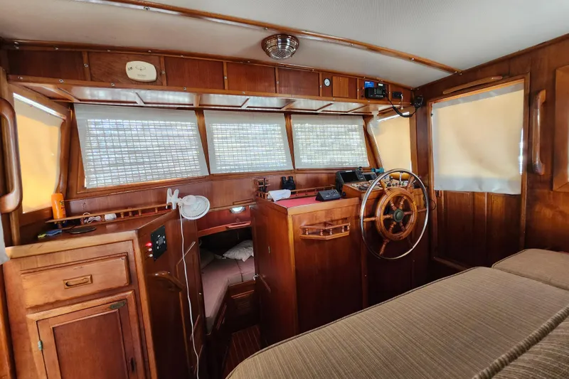 Slide: The Image of 1988 Sundowner Tug 30 interior with wooden helm, cozy cabin, and nautical decor. - 17