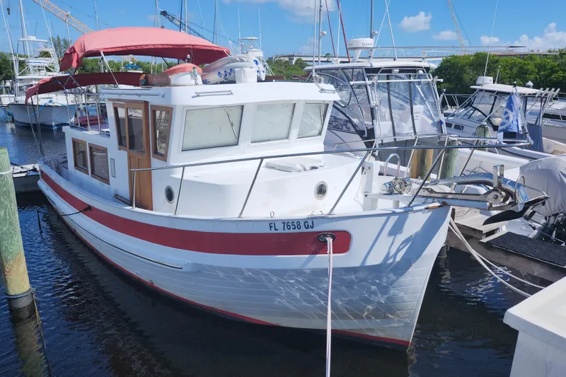 Slide: The Image of 1988 Sundowner Tug 30 docked, featuring red canopy and white hull in marina setting. - 2