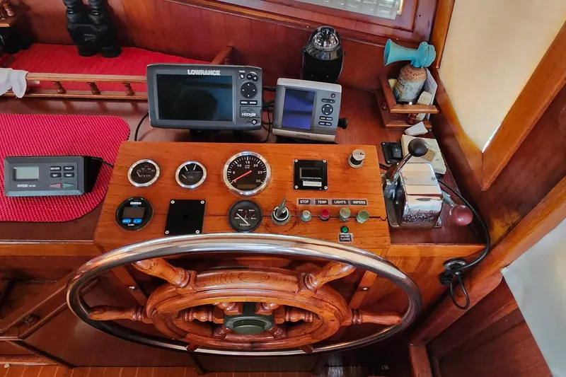 Slide: The Image of 1988 Sundowner Tug 30 helm with wooden wheel, gauges, and navigation equipment. - 23