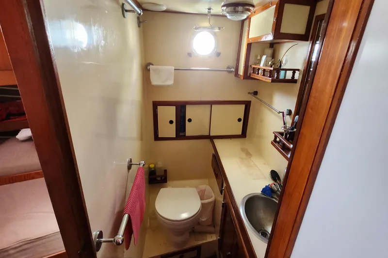 Slide: The Image of Compact bathroom in 1988 Sundowner Tug 30, featuring toilet, sink, and wooden cabinetry. - 27