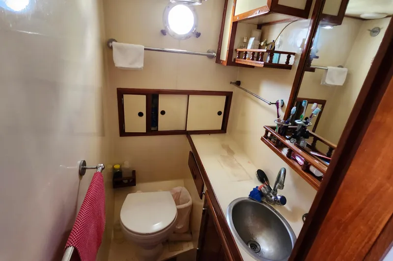 Slide: The Image of Compact bathroom in 1988 Sundowner Tug 30, featuring sink, toilet, and storage cabinets. - 28