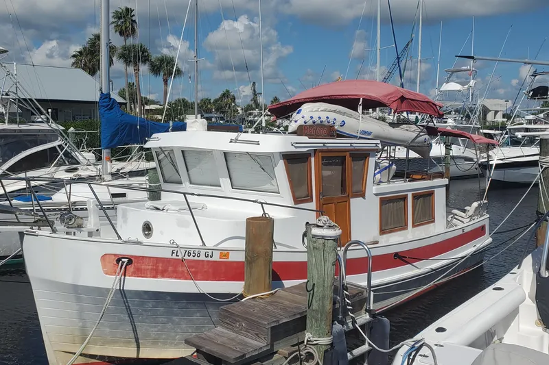 Slide: The Image of 1988 Sundowner Tug 30 docked at marina, featuring red accents and a covered deck. - 3