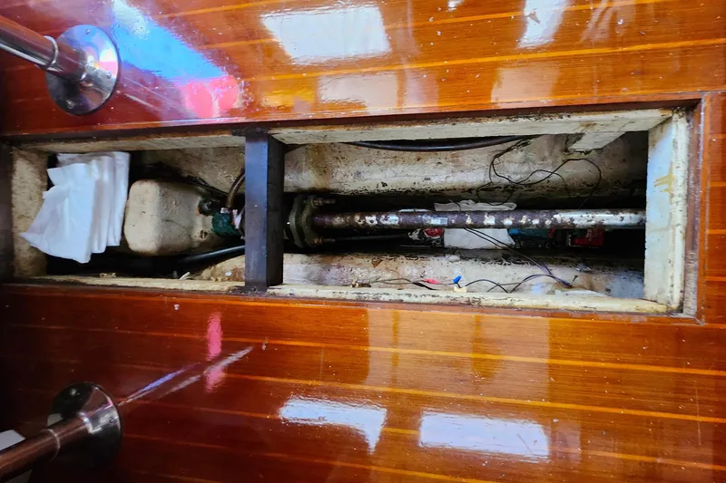 Slide: The Image of 1988 Sundowner Tug 30 interior showing exposed mechanical components beneath wooden floor. - 34