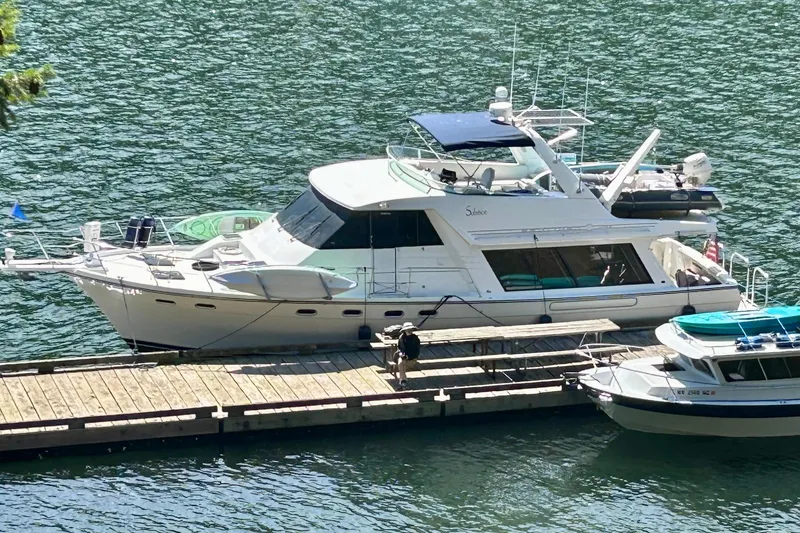 The Image of 2000 Bayliner 4788 Pilot House Motoryacht docked on calm water. - 0
