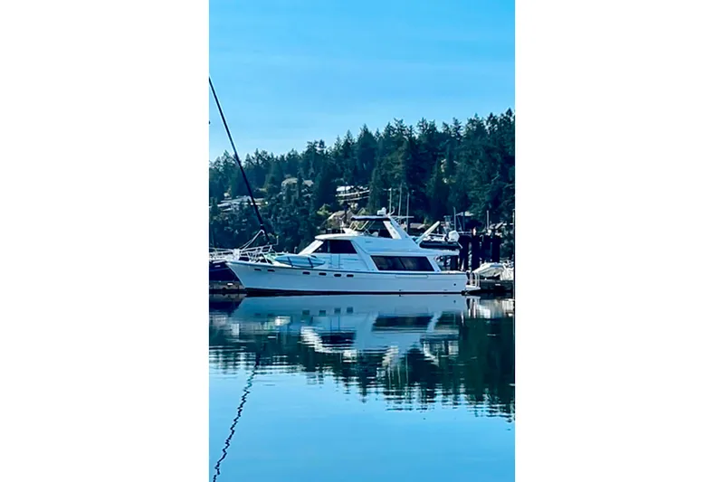 Slide: The Image of Bayliner 4788 Pilot House Motoryacht 2000 docked on calm water with forest backdrop. - 1