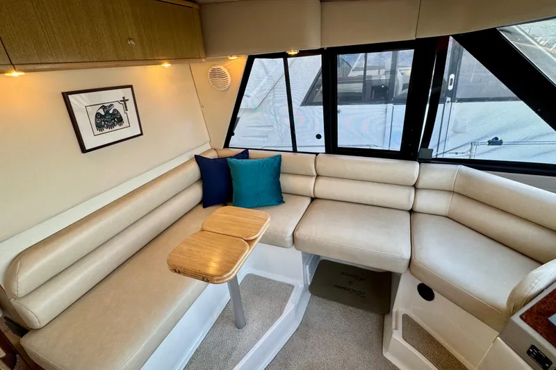 Slide: The Image of 2000 Bayliner 4788 Pilot House Motoryacht interior with beige seating and wooden table. - 24