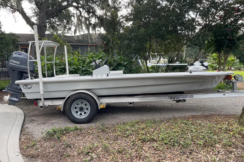 Slide: The Image of 2023 Riptide 17 Flats boat on trailer, parked outdoors with lush greenery. - 0