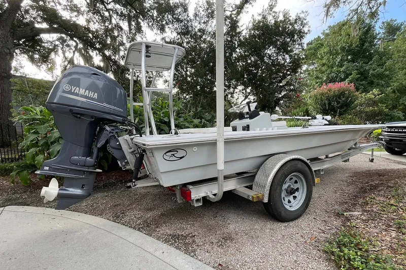 Slide: The Image of 2023 Riptide 17 Flats boat with Yamaha engine on trailer, surrounded by greenery. - 1