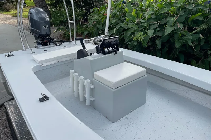 Slide: The Image of 2023 Riptide 17 Flats boat with seating and motor, surrounded by greenery. - 12