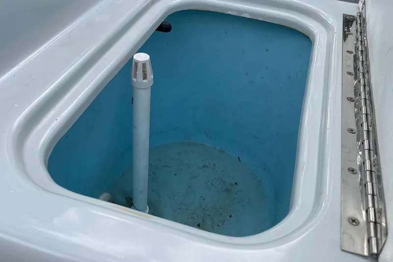 Slide: The Image of Livewell interior of 2023 Riptide 17 Flats boat, featuring blue lining and drainage pipe. - 20
