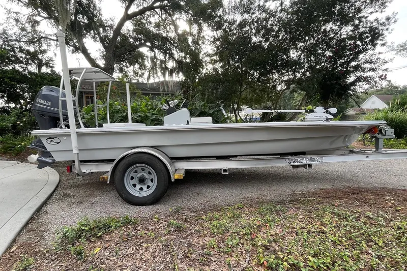 Slide: The Image of 2023 Riptide 17 Flats boat on trailer, parked outdoors with lush greenery. - 3