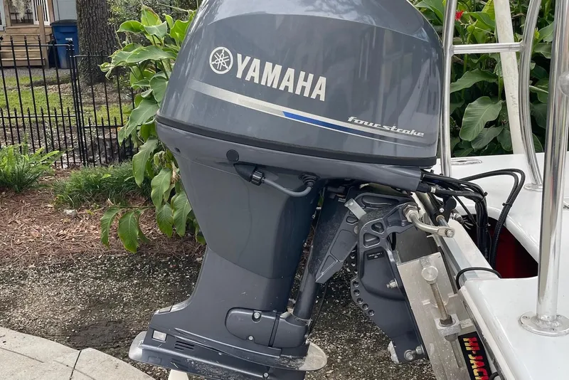 Slide: The Image of 2023 Riptide 17 Flats boat with Yamaha four-stroke outboard motor, parked near greenery. - 32