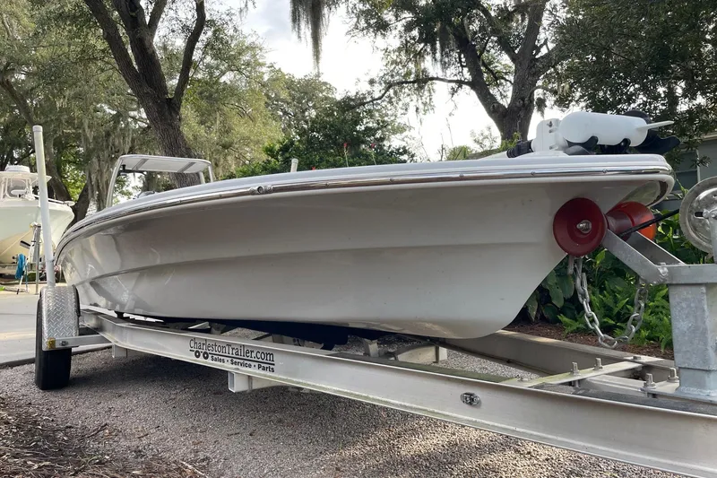 Slide: The Image of 2023 Riptide 17 Flats boat on trailer, surrounded by trees. - 5