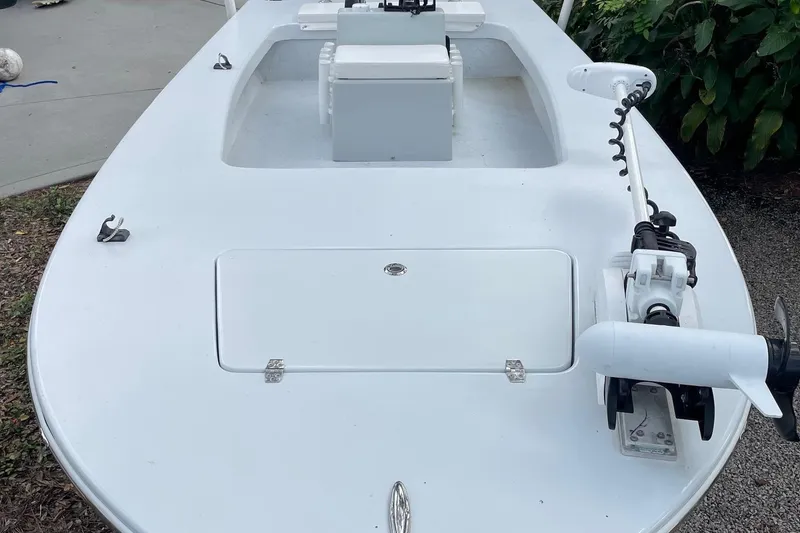 Slide: The Image of 2023 Riptide 17 Flats boat with trolling motor and storage compartment, parked outdoors. - 8