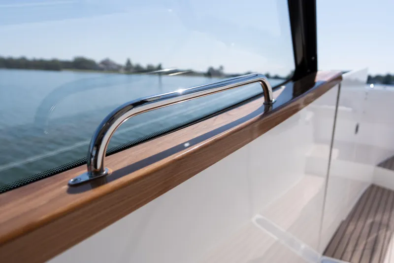 Slide: The Image of 2023 MJM Yachts 4, sleek chrome railing, wooden trim, scenic water view. - 52