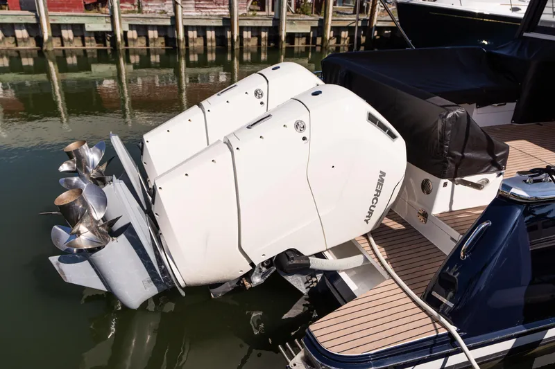 Slide: The Image of Twin Mercury outboard engines on a 2023 MJM 4 boat, docked by the water. - 64