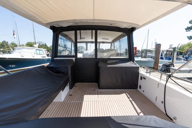 Slide: The Image of 2023 MJM 4 boat interior with covered seating and docked yachts in background. - 65