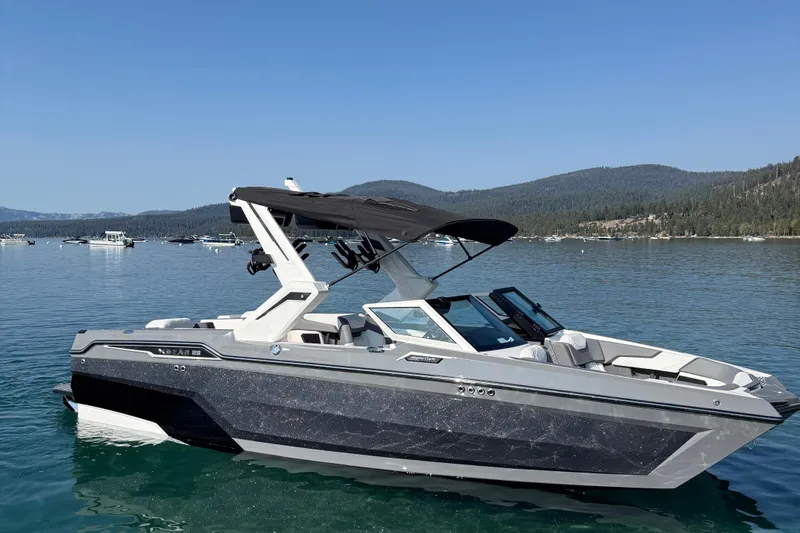 Slide: The Image of 2026 MasterCraft XStar 23 boat on a serene lake with mountainous backdrop. - 1