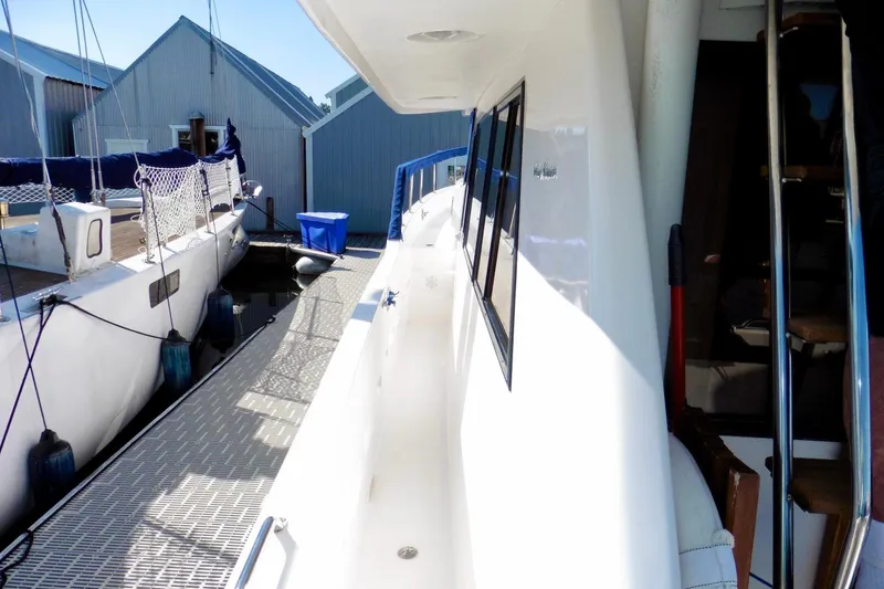 Slide: The Image of 2000 Ocean Alexander 423 Classico yacht on calm water, featuring blue canopy and American flag. - 4