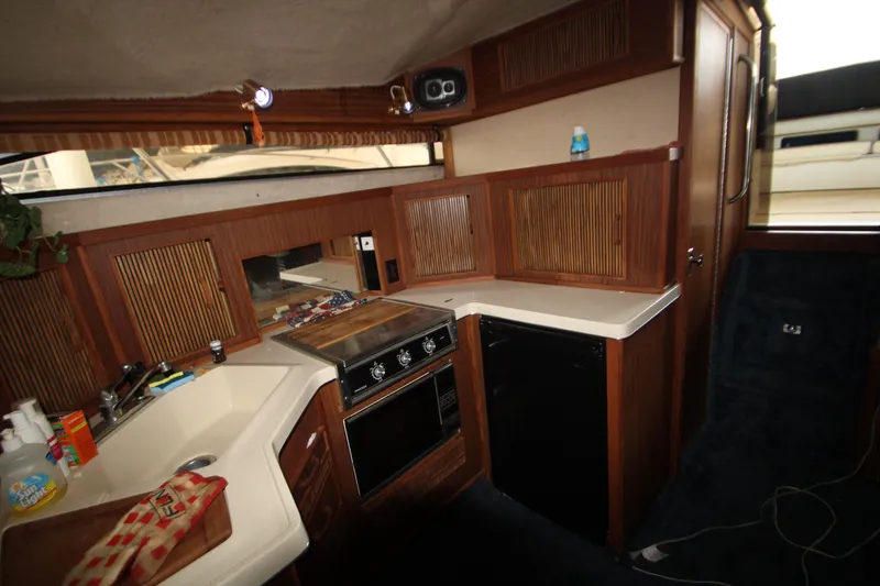 Slide: The Image of Interior of 1986 Sea Ray 340 Sundancer boat featuring a compact kitchen area. - 21