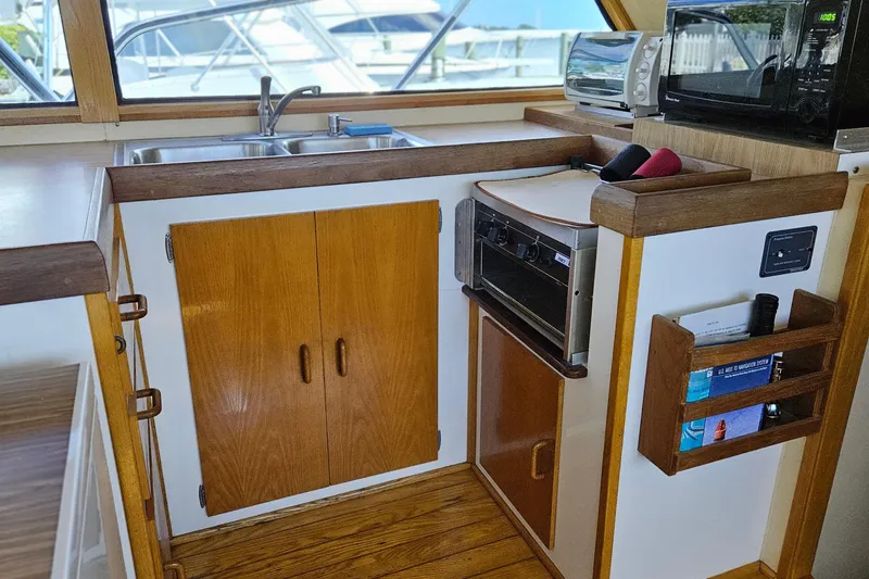 Slide: The Image of 1989 Breaux Brothers Sportfisherman kitchen with wooden cabinets, sink, and appliances. - 12