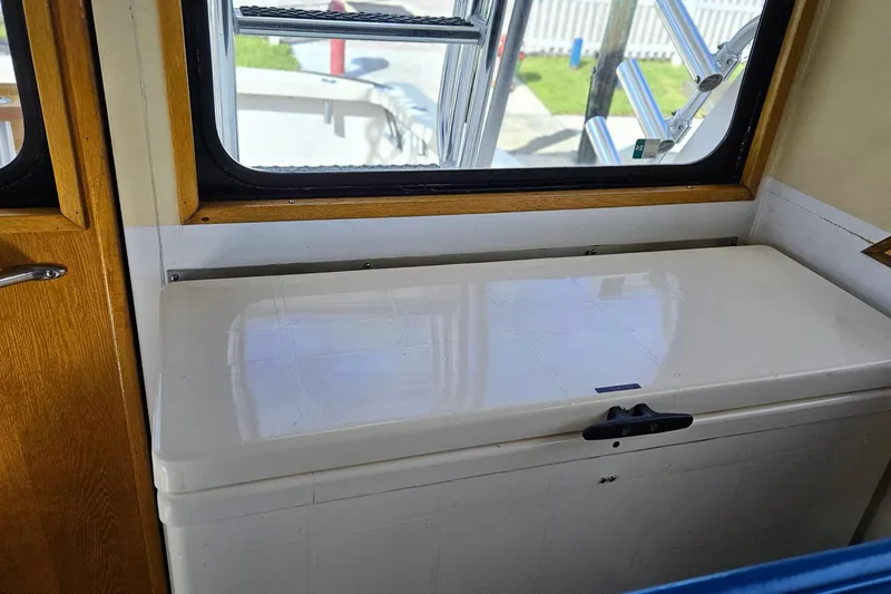 Slide: The Image of 1989 Breaux Brothers Sportfisherman interior with white storage bench and wooden accents. - 17